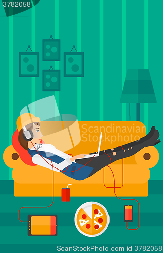 Image of Woman lying on sofa with many gadgets.