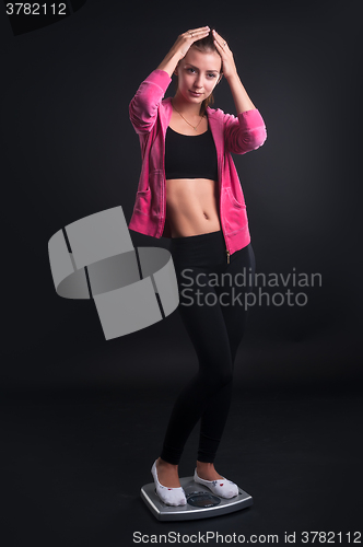 Image of Sad young woman on weight scales
