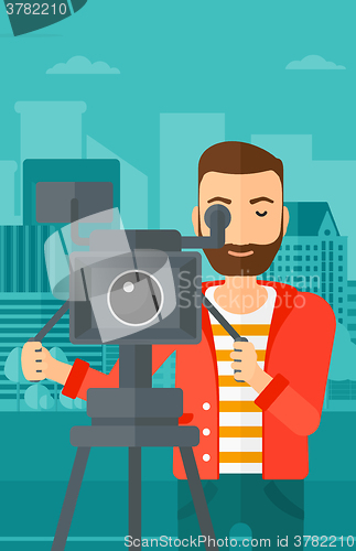 Image of Cameraman with movie camera on a tripod.