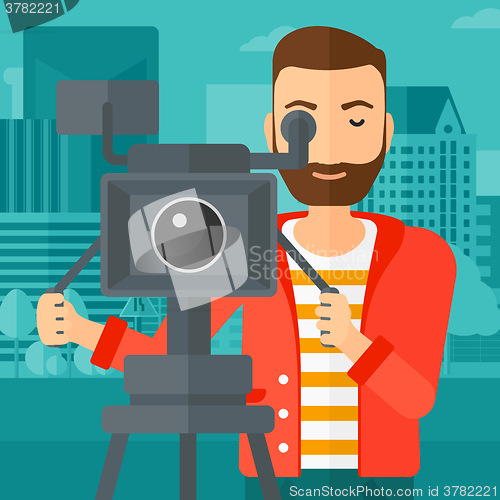 Image of Cameraman with movie camera on a tripod.