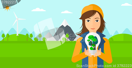 Image of Woman with lightbulb and trees inside.