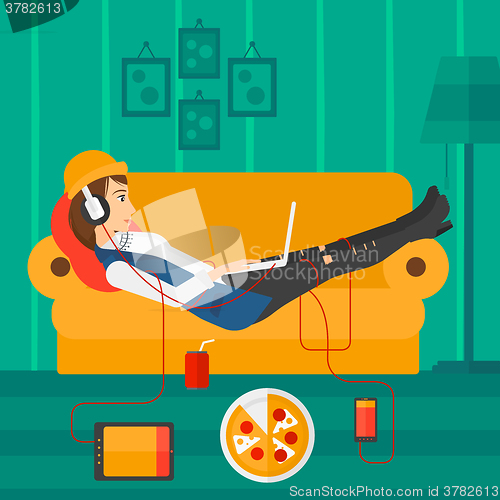 Image of Woman lying on sofa with many gadgets.