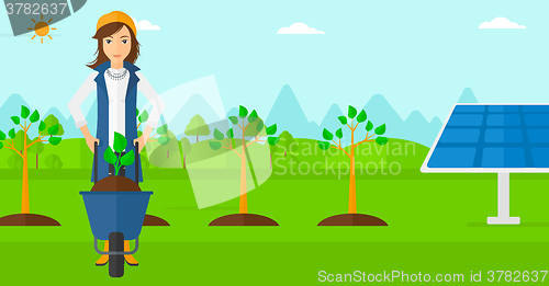 Image of Woman with plant and wheelbarrow.