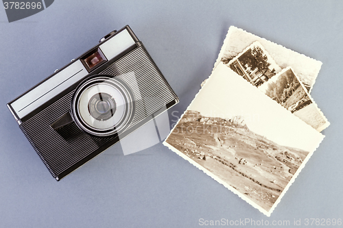 Image of Vintage photo camera and old photos on a gray table