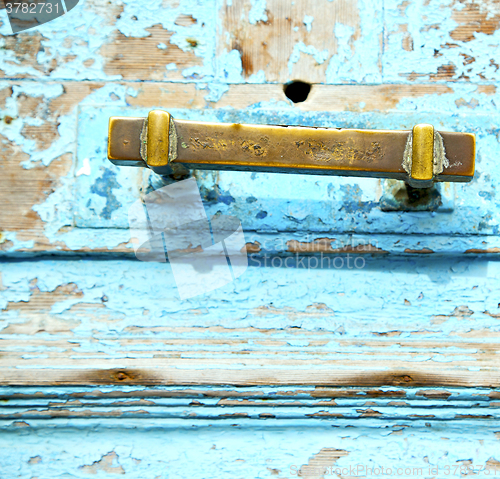 Image of rusty metal nail dirty stripped paint in the blue wood door and 