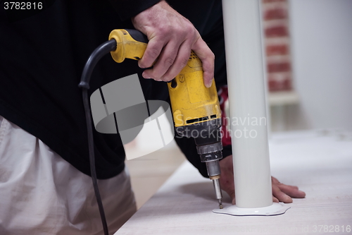 Image of repairman working with drilling machine