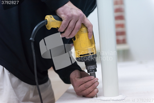 Image of repairman working with drilling machine