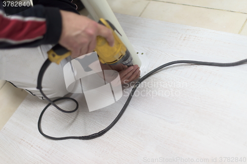 Image of repairman working with drilling machine