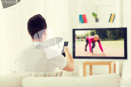 Image of man watching sport channel on tv at home