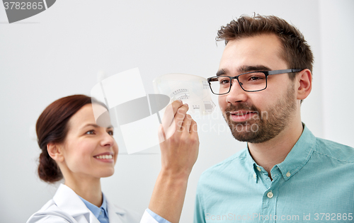 Image of optometrist with ruler and patient at eye clinic