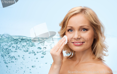 Image of happy woman cleaning face with cotton pad