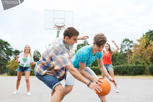 Image of group of happy teenagers playing basketball