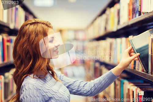 Image of happy student girl or woman with book in library