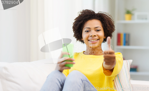 Image of happy african woman with smartphone at home