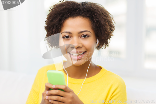 Image of happy african woman with smartphone and earphones
