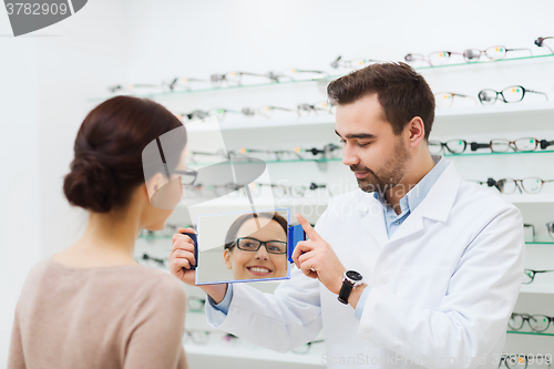 Image of woman in glasses looking to mirror at optics store