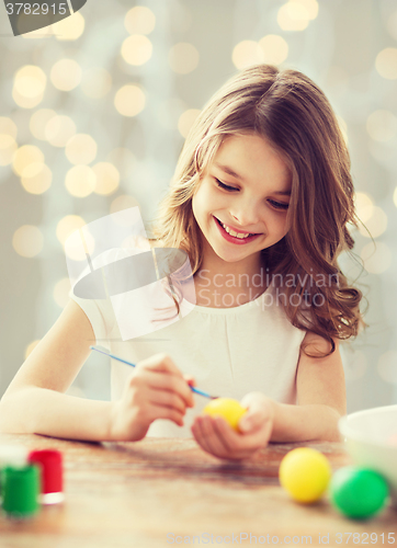 Image of close up of girl with brush coloring easter eggs