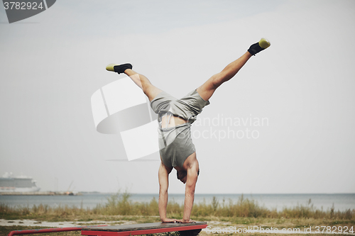 Image of young man exercising on bench outdoors