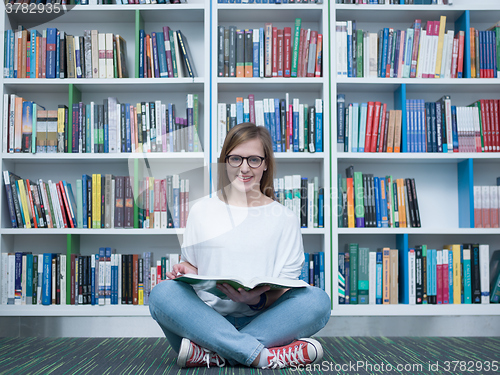 Image of student girl reading book in library