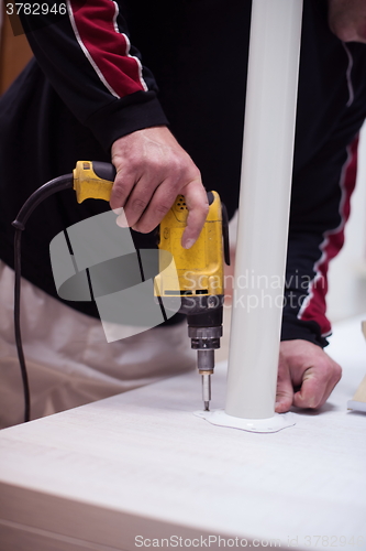 Image of repairman working with drilling machine