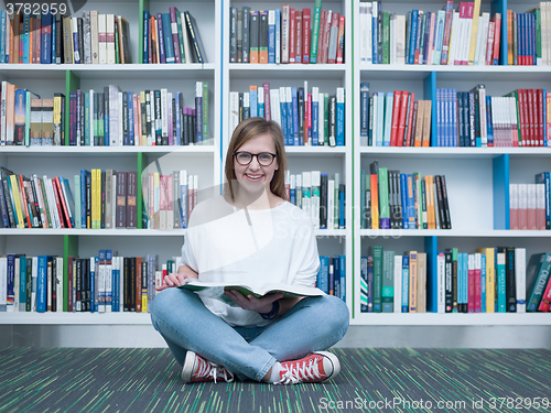 Image of student girl reading book in library