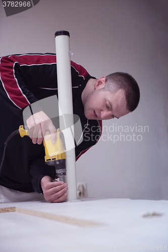 Image of repairman working with drilling machine