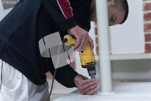 Image of repairman working with drilling machine