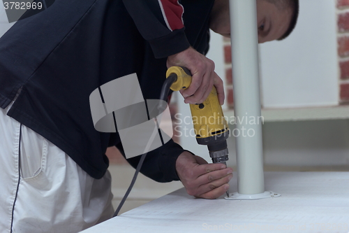 Image of repairman working with drilling machine