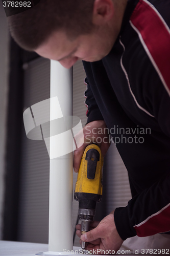 Image of repairman working with drilling machine