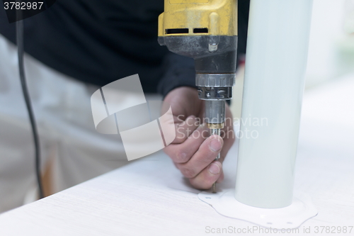 Image of repairman working with drilling machine