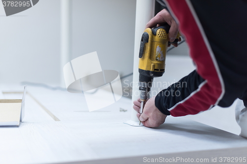 Image of repairman working with drilling machine