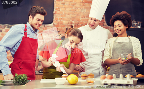 Image of happy friends and chef cook baking in kitchen