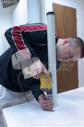 Image of repairman working with drilling machine