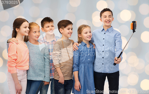 Image of happy children with smartphone and selfie stick