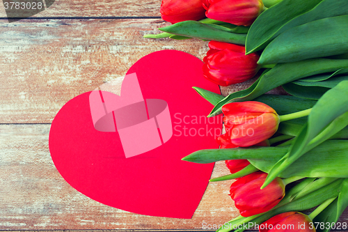 Image of close up of red tulips and paper heart shape card