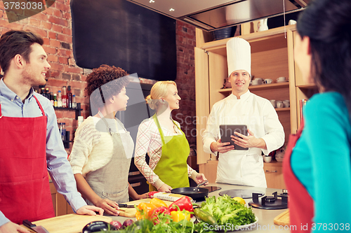 Image of happy friends with tablet pc in kitchen