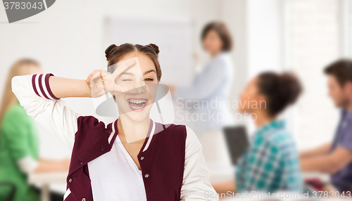 Image of happy teenage girl showing peace sign at school