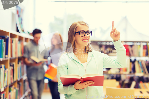 Image of happy student girl or woman with book in library