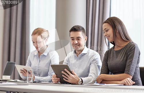Image of smiling business people with tablet pc in office