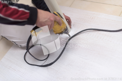 Image of repairman working with drilling machine