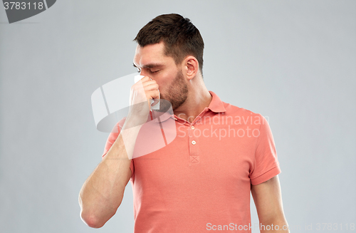 Image of sick man with paper napkin blowing nose