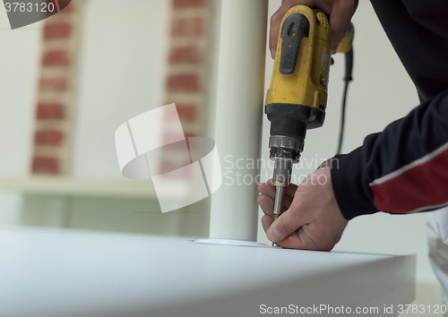 Image of repairman working with drilling machine