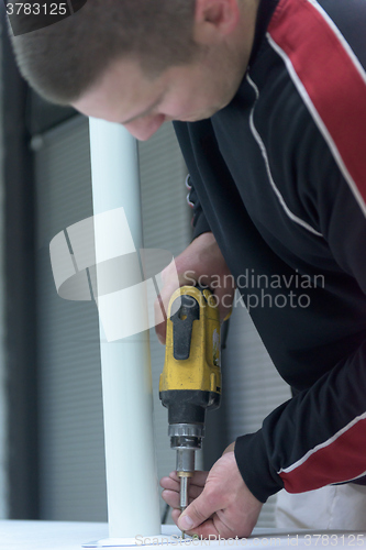 Image of repairman working with drilling machine