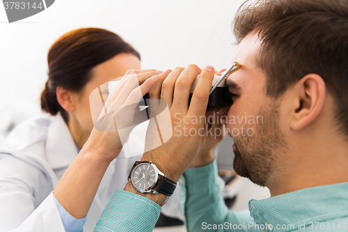 Image of optician with pupillometer and patient at clinic