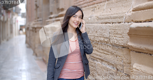 Image of Young woman walking through town with her mobile