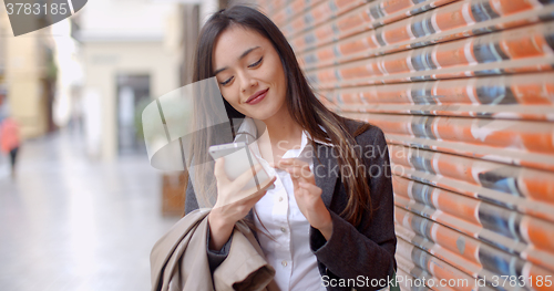 Image of Young woman using her mobile in town