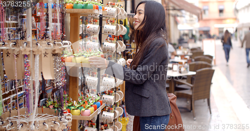 Image of Smiling young woman checking out shop merchandise