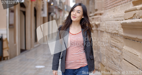 Image of Young woman walking through an alley in town