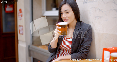Image of Young woman relaxing enjoying a beer