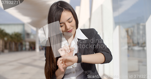 Image of Young woman checking her wristwatch for the time